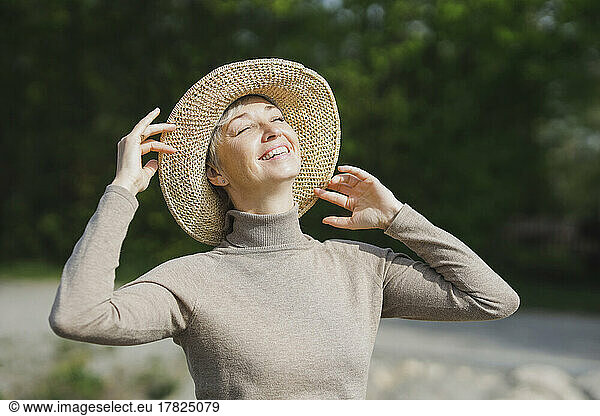 Happy mature woman with eyes closed enjoying sunny day