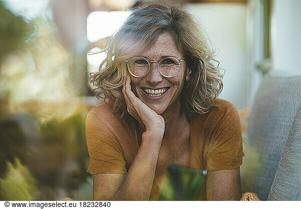 Happy mature woman with smart phone seen through glass