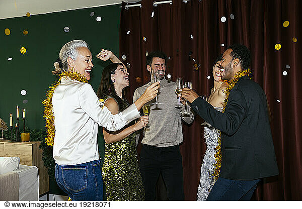 Happy men and women with drinking glasses dancing at new year party
