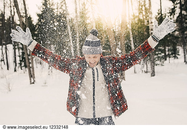 Happy mid adult man playing with snow on snow covered field