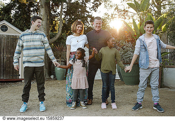 Happy mixed-race family laughing and holding hands