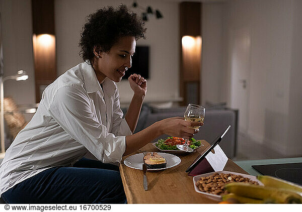 Happy mixed race woman proposing toast during online date