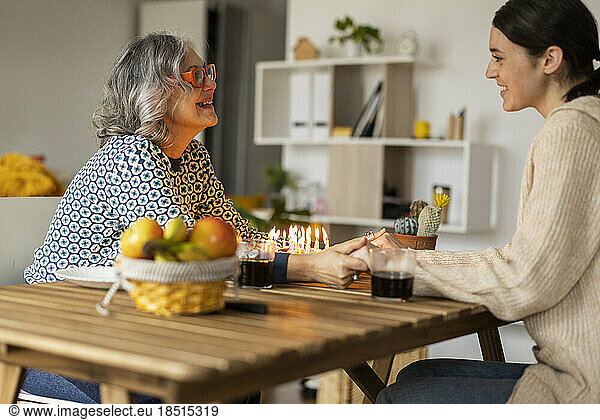 Happy mother and daughter celebrating birthday and talking to each other at home