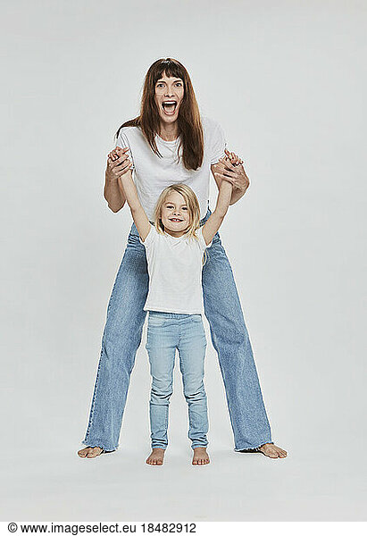 Happy mother and daughter having fun against white background