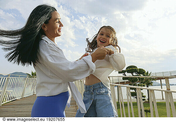 Happy mother and daughter having fun on bridge