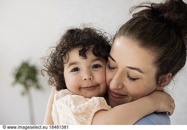 Happy mother and daughter hugging with eyes closed