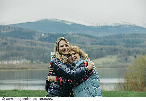 Happy mother and daughter hugging with mountain in background