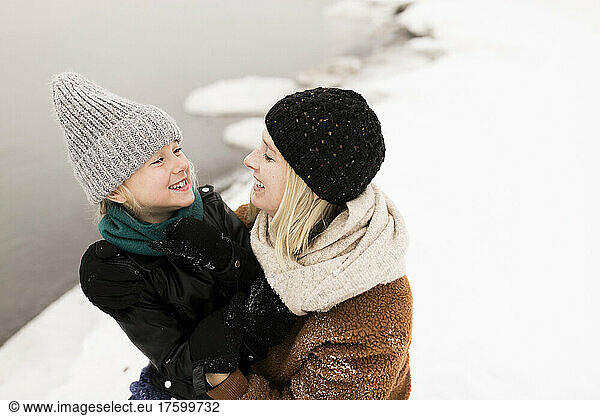 Happy mother and daughter looking at each other in winter