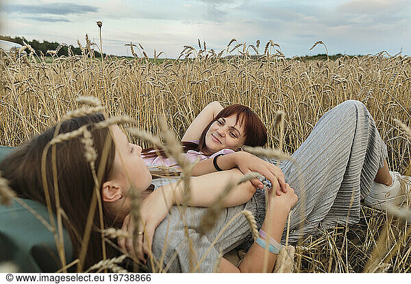 Happy mother and daughter lying in field