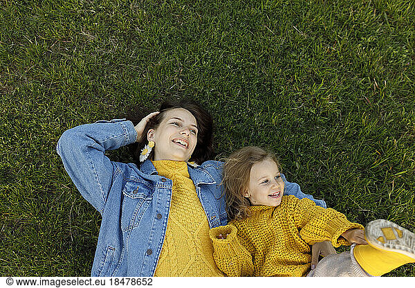 Happy mother and daughter lying on grass in park