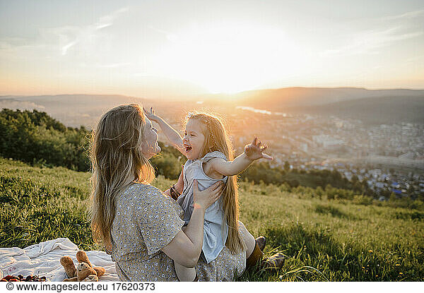 Happy mother and daughter spending timein nature at sunset