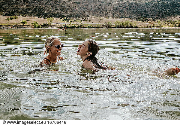 Happy mother and daughter swimming in a lake on a summer day
