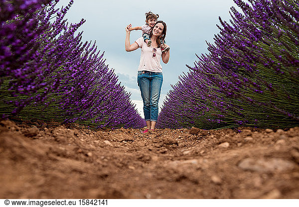 Happy mother and daughter walking among lavender fields in the summer