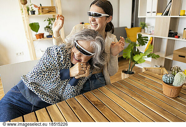 Happy mother and daughter wearing smart glasses having fun at home