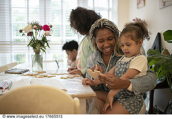 Happy mother and daughter with jigsaw piece at table