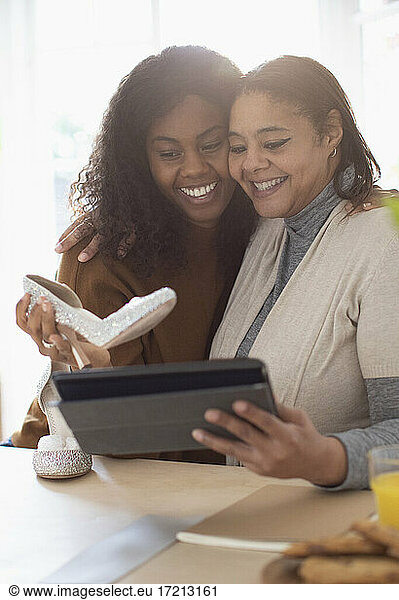 Happy mother and daughter with wedding shoes and digital tablet
