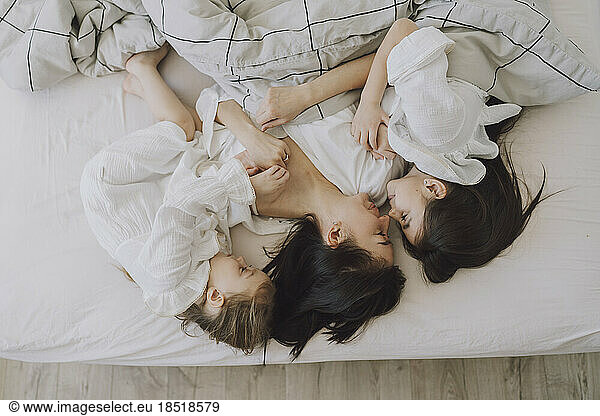 Happy mother and daughters in bed