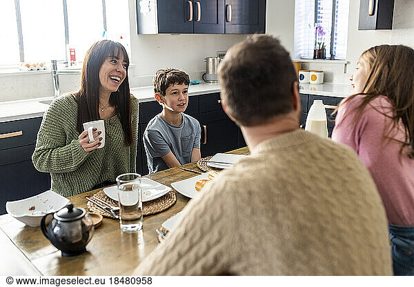 Happy mother and father having breakfast with children together at home