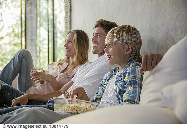 Happy mother and father with son watching TV at home