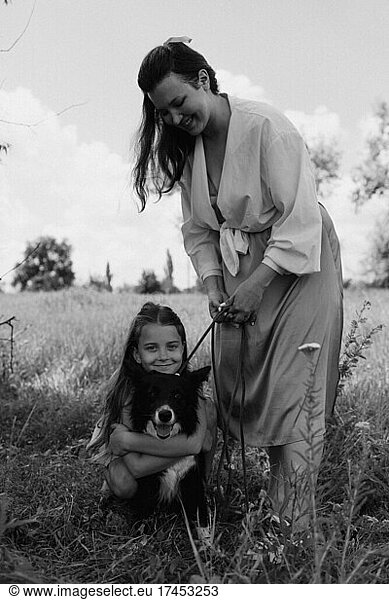 Happy mother and girl with dog outdoors. Pet care concept.