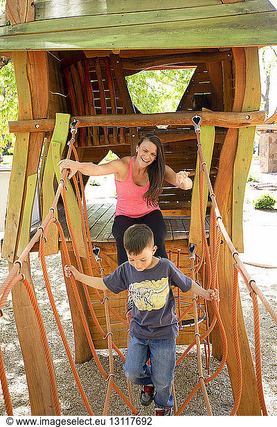Happy mother and son playing on outdoor play equipment at playground