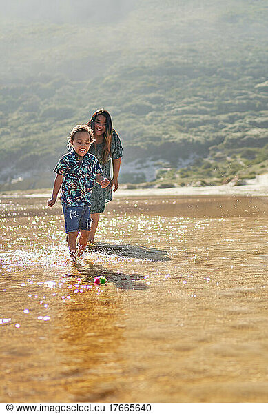 Happy mother and son playing with ball in ocean surf