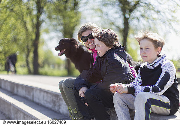 Happy mother and sons with dog in sunny park