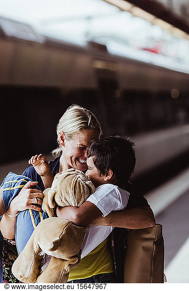 Happy mother carrying son while standing at train station
