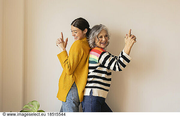 Happy mother gesturing with daughter in front of wall