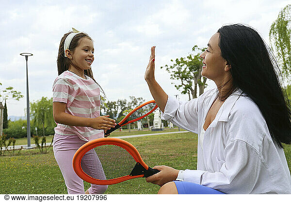 Happy mother giving high-five to daughter in park