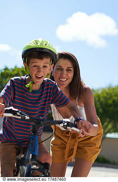 Happy mother helping son ride bike