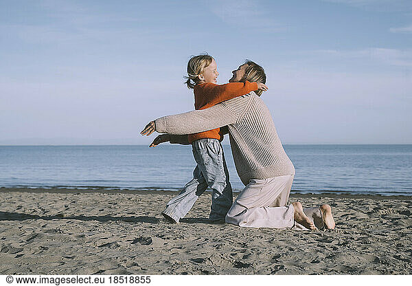 Happy mother hugging daughter at beach