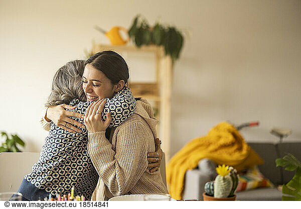 Happy mother hugging daughter in living room at home