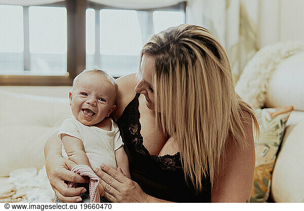 Happy mother looking at baby boy while sitting at home