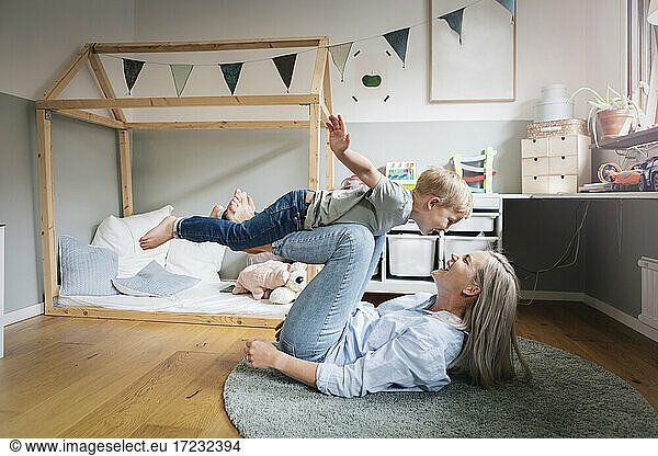 Happy mother playing with son in bedroom