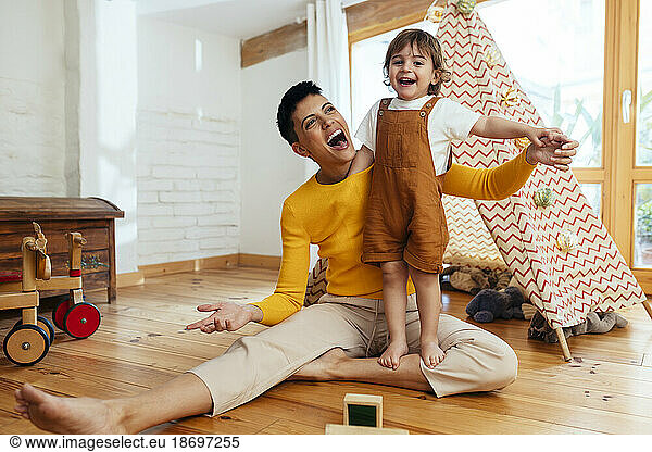 Happy mother playing with son in living room at home