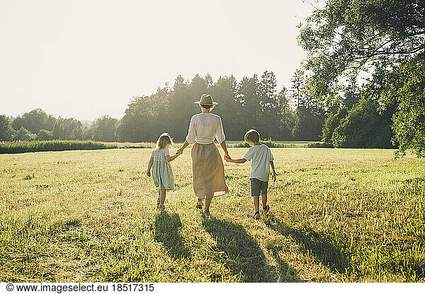 Happy mother walking with son and daughter on sunny day