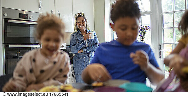 Happy mother watching kids bake in kitchen