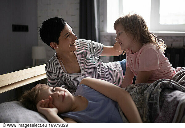 Happy mother with daughters in bed in morning