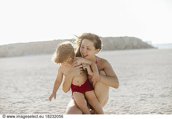 Happy mother with shirtless boy enjoying at beach