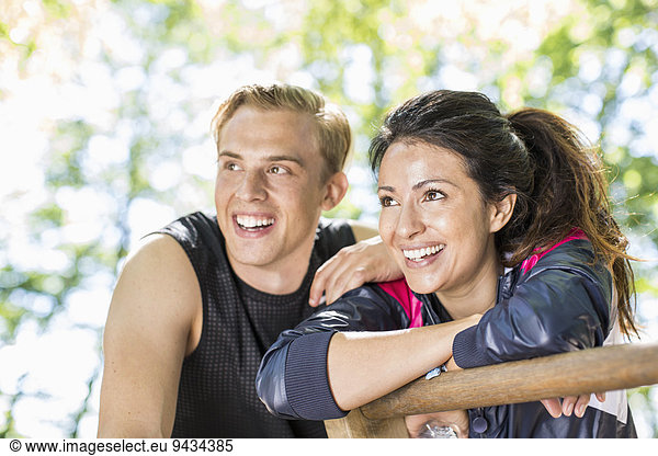 Happy multi-ethnic couple looking away at outdoor gym