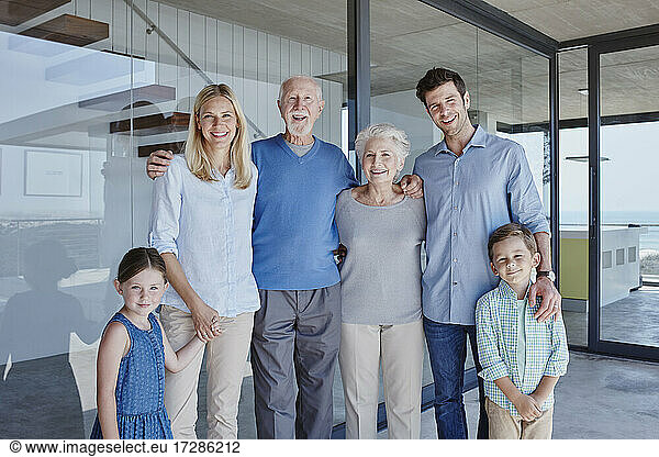 Happy multi-generation family standing together in front of glass wall