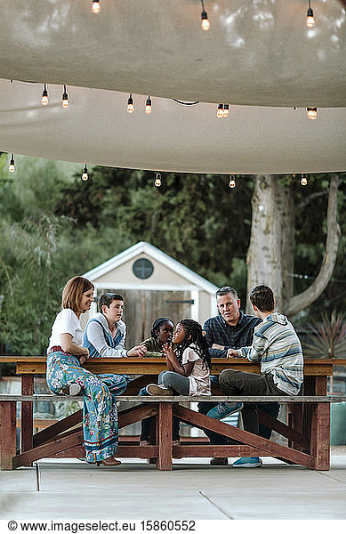 Happy multiracial family at picnic table under sunshade