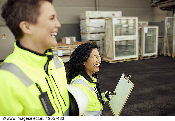 Happy multiracial female colleagues walking in distribution warehouse