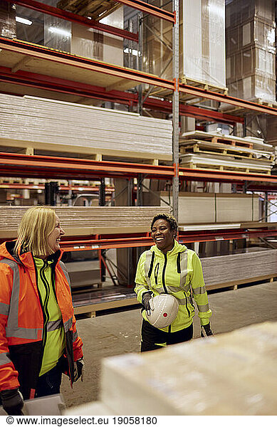 Happy multiracial female coworkers standing in distribution warehouse