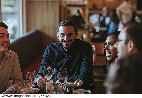 Happy multiracial male and female friends having wine in restaurant