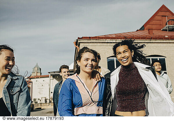 Happy multiracial young women with friends enjoying in city