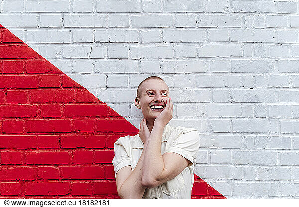 Happy non-binary person standing in front of two toned wall