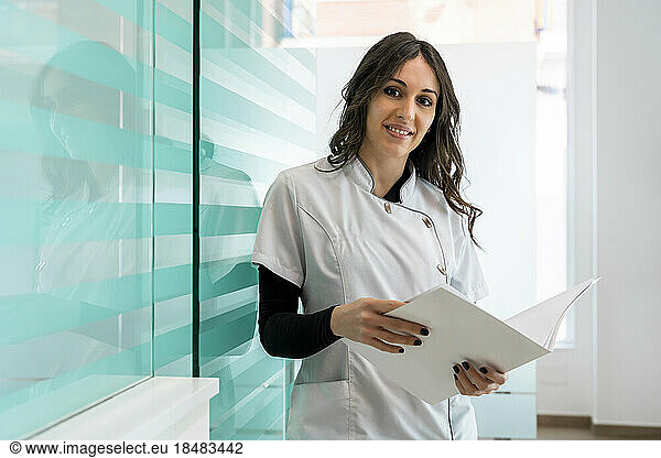 Happy nurse with documents standing at clinic
