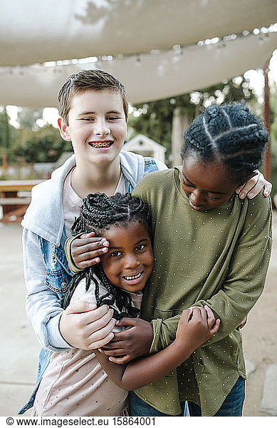 Happy outdoor group hug with smiling multiracial siblings